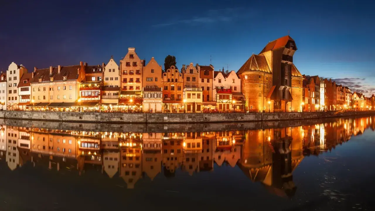 Nadmorska panorama Gdańska nocą, z odbijającymi się w wodzie kamienicami i Żurawiem. Idealne miejsce na zaręczyny Polska.