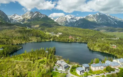 Malownicze jezioro otoczone lasem i górami, z hotelami w tle. Słowacja atrakcje turystyczne w pełnej krasie.