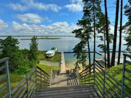 Drewniane schody prowadzą do jeziora, gdzie cumuje statek. Idealne miejsce, by zapytać: gdzie na Mazury?