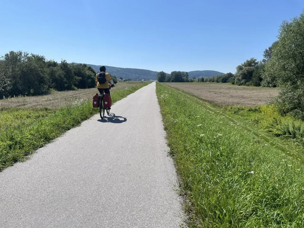 Rowerzysta przemierza malownicze jezioro rożnowskie trasy rowerowe. Słoneczny dzień sprzyja podr&oacute;ży przez zielone pola i lasy.